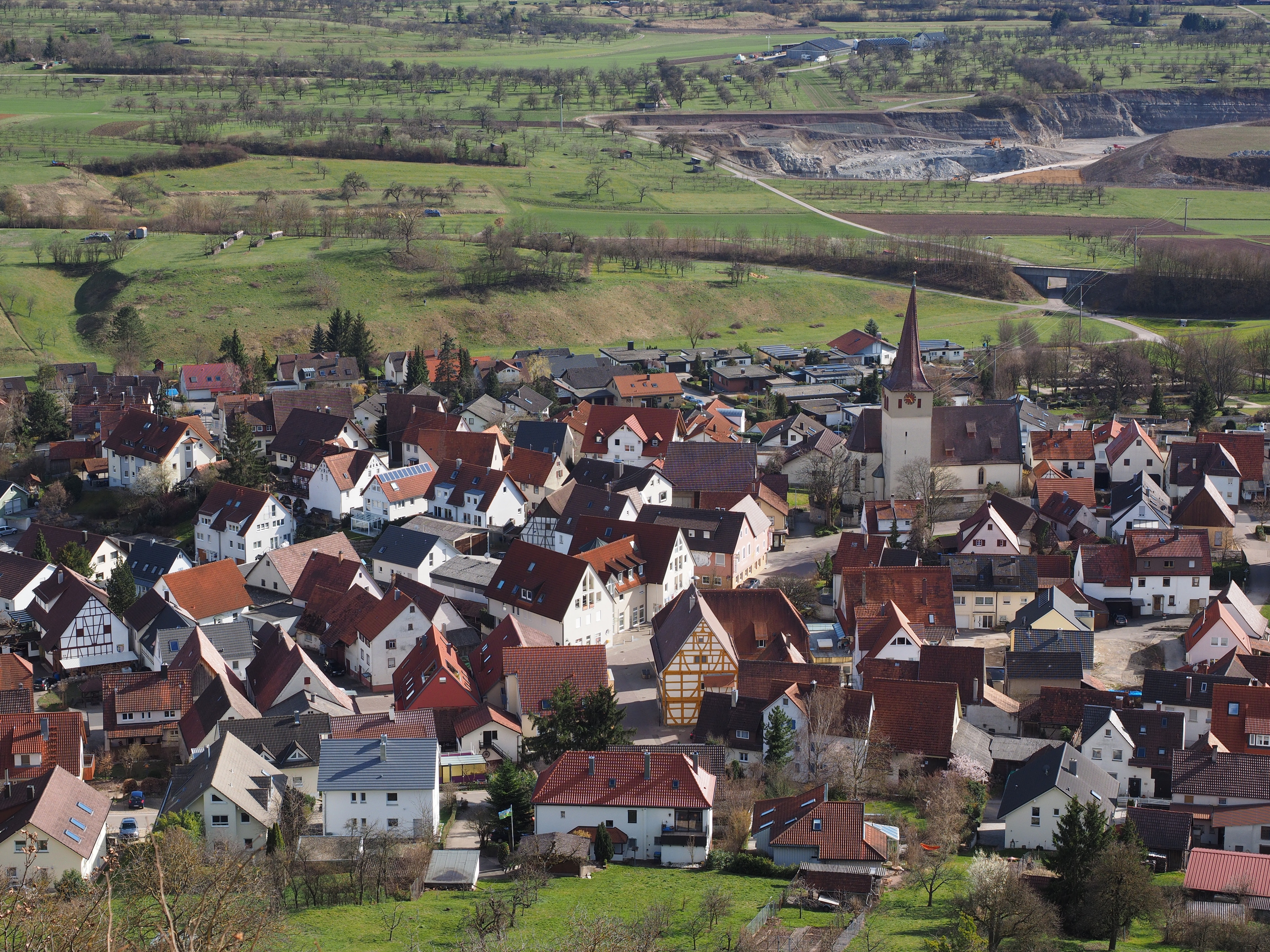 A hillside town of houses and a church, surrounded by green fields